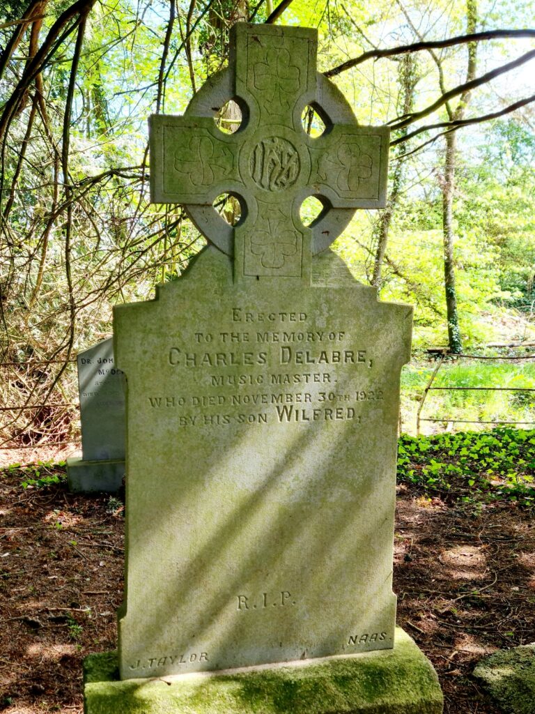 Granite headstone topped with a celtic cross and inscribed with the words - Erected to the meory of Charles Delabre Music MAster who died November 30th 1922 by his son Wilfred. RIP. J. Taylor. Naas. 