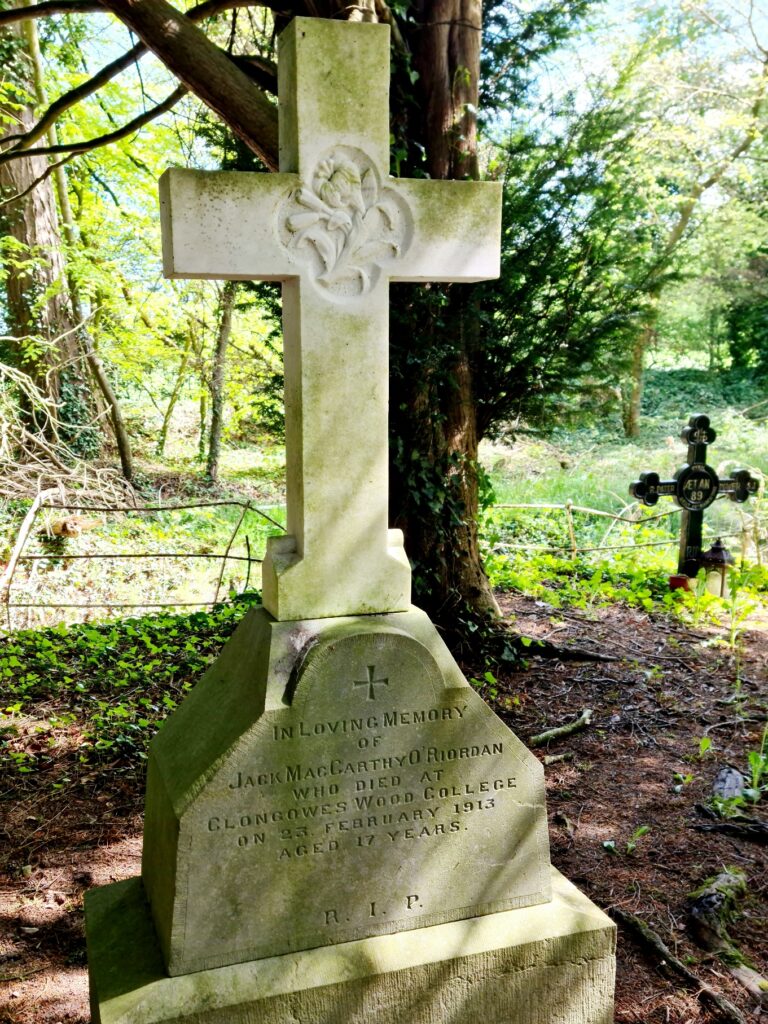 White marble cross with the following inscription on the base - In loving memory of Jack MacCarhty O'Riordan who died at Clongowes Wood College 23 February 1913 aged 17 years. RIP. 