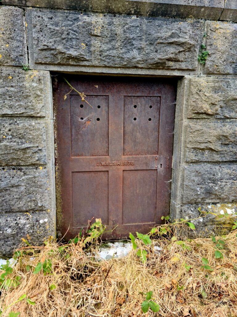 Brown metal rusted door with the words J Walsh 1878