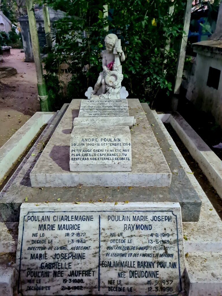 Gravestone with a statue of a boy angel nursing a cross and a wreath. The inscription is in French. Andre Poulain, 20 Juin 1902-Septembre 1, 1904. Petit Ange cheri, tu as ete nos plus cheres esperances. Tu resteras nos eternels regrets.