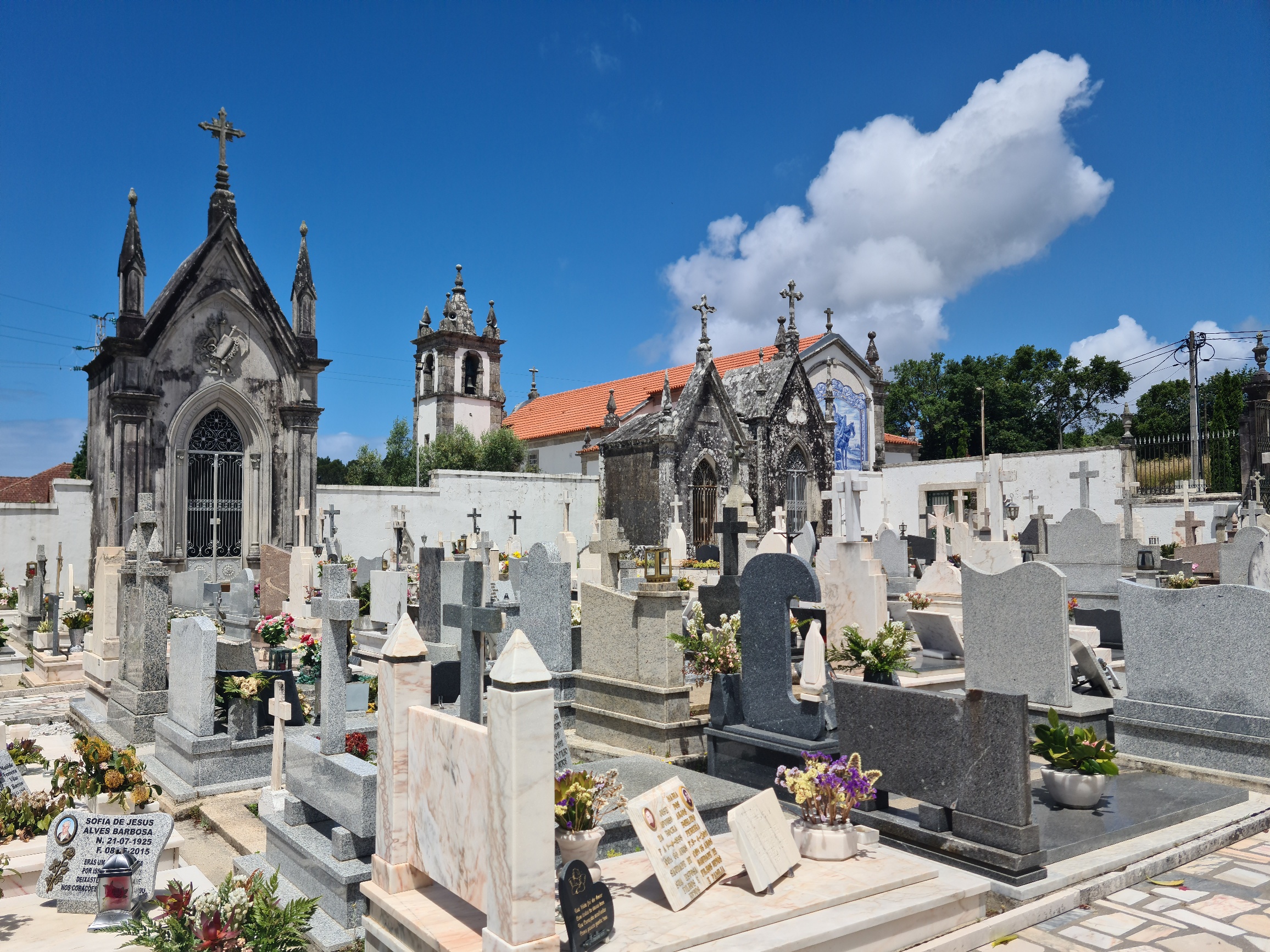 Cemetery with graves in the foreground and a red-roofed church in the background. it offers a glimpse of the blue-and-white tiled fresco of St Martin
